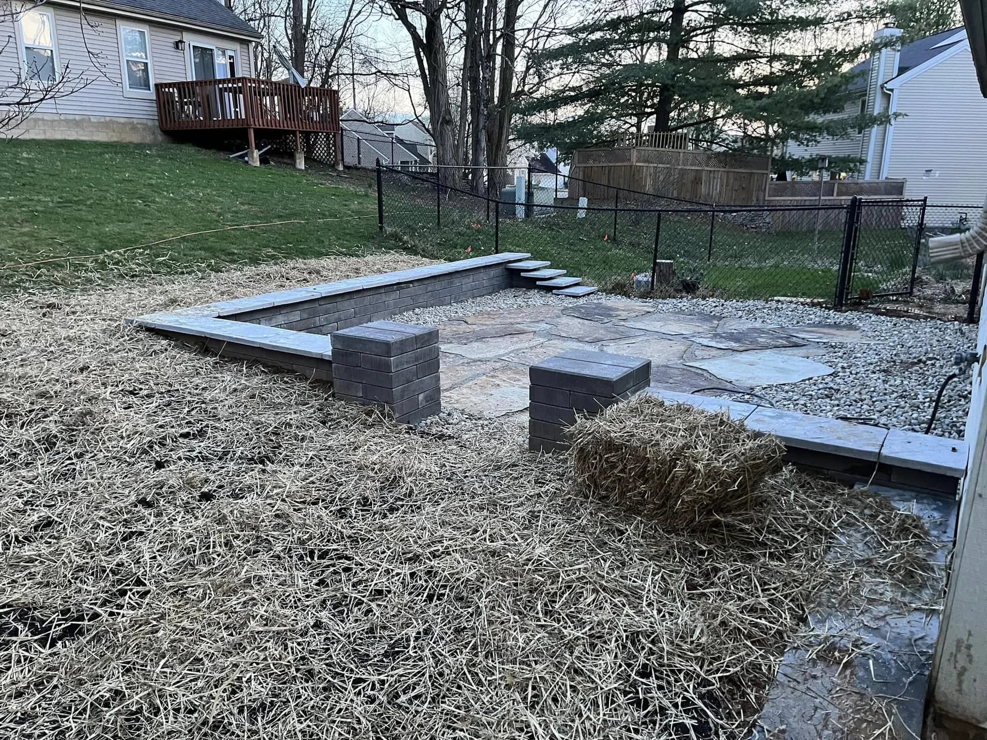 Completed flagstone patio with retaining walls, built-in seating, and stone steps
